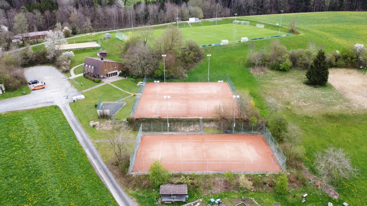 Luftaufnahme der Sportanlage Mettlen mit drei Tennisplätzen, dem Klubhaus und einem Fussballplatz.